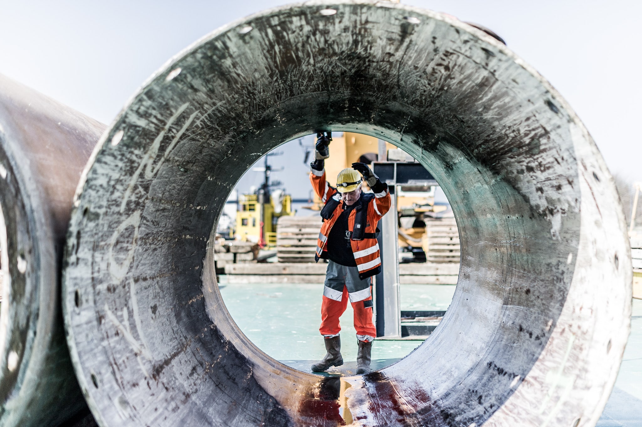 Arbeiter in Schutzkleidung mit großes Metallrohr auf einer Baustelle