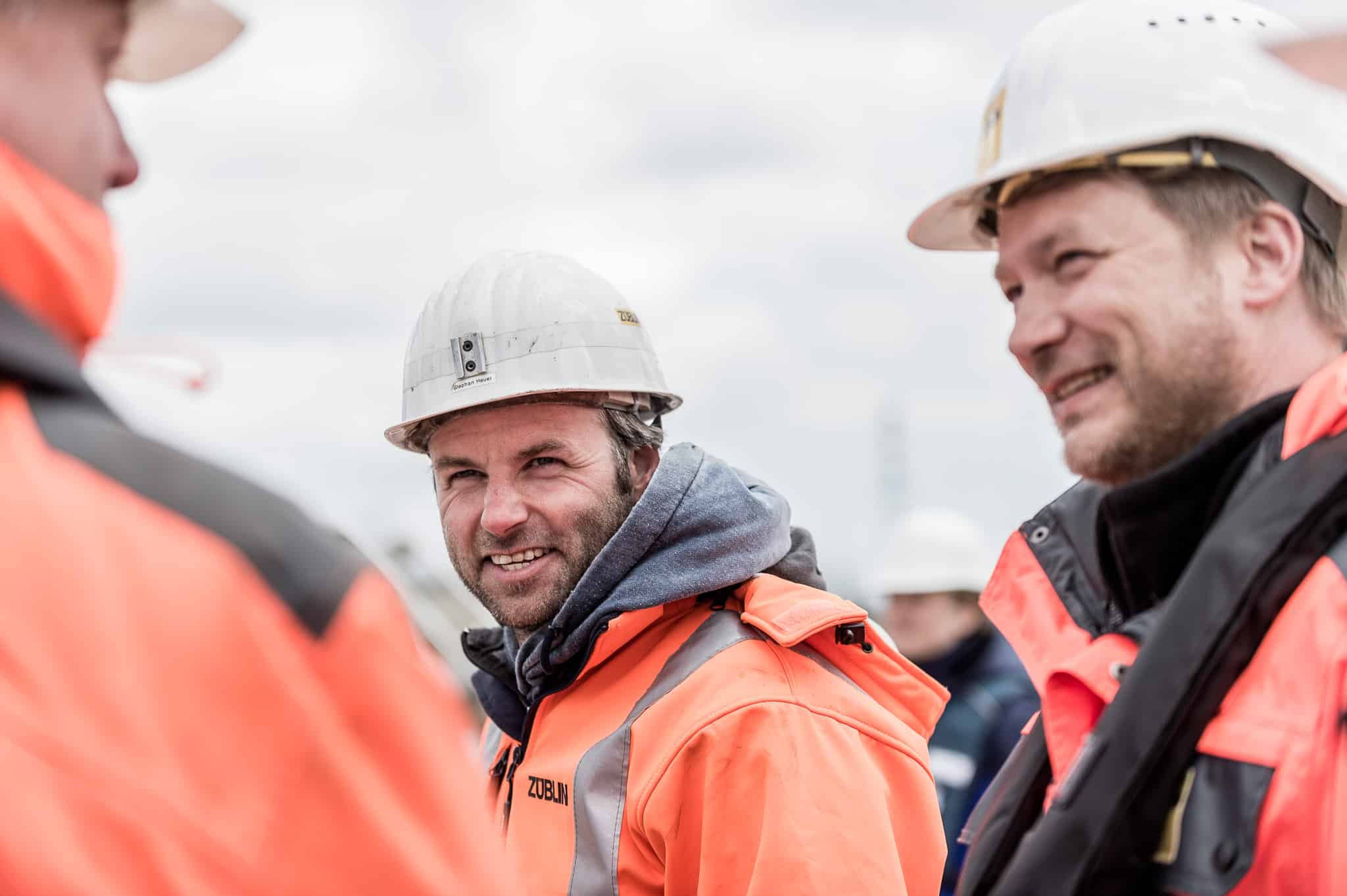 Bauarbeiter in Warnkleidung und Helmen auf einer Baustelle im Gespräch