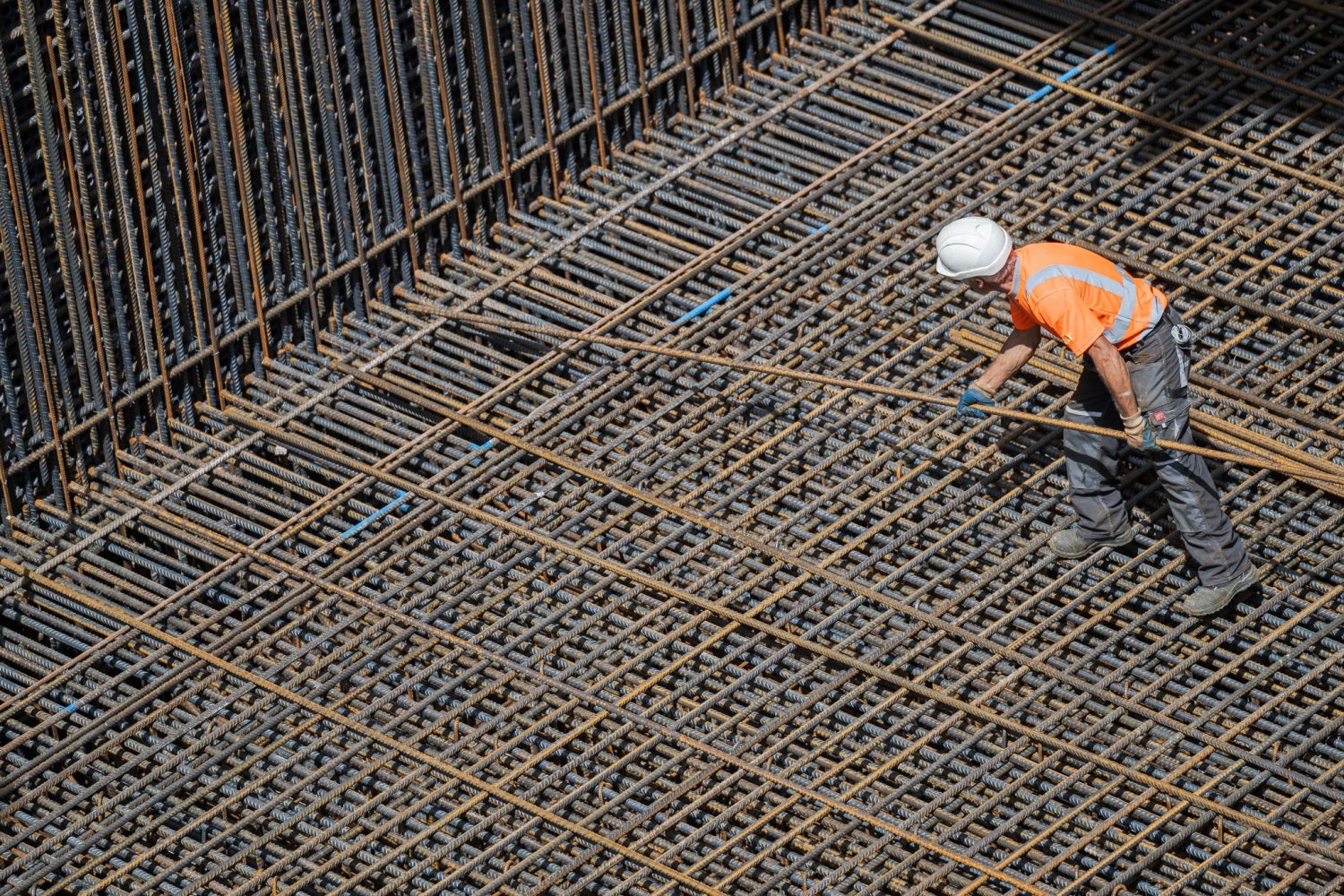 Bauarbeiter verlegt Bewehrungsstahl in einem Beton-Fundament